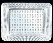 Esta imagem mostra um refletor de LED retangular. No centro, há uma placa plana com dezenas de pequenos pontos de luz organizados em linhas e colunas. Ao redor dessa placa, as paredes internas são prateadas e facetadas para refletir e espalhar a luz intensamente.