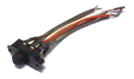 
A imagem mostra uma chave inversora de tensão pequena e preta, com um botão deslizante no centro. Dela saem seis fios coloridos (marrom, vermelho e branco). Esse componente é comum em aparelhos bivolt para alternar manualmente entre 110V e 220V.