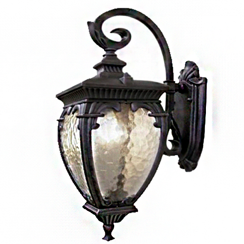 Uma arandela colonial de parede em metal preto. Possui um braço curvado em "S" com detalhes de folhas. O corpo principal tem formato de sino com vidros martelados e texturizados. O acabamento é clássico e elegante, ideal para áreas externas ou fachadas rústicas.