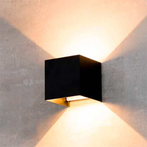 
Esta arandela preta é um cubo minimalista fixado à parede. Ela emite luz para cima e para baixo, criando dois grandes triângulos luminosos que se expandem contra a superfície, proporcionando uma iluminação indireta, elegante e moderna para ambientes internos ou externos.