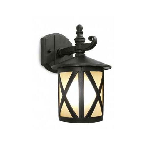 
Uma arandela de parede estilo colonial em metal preto. Possui base retangular fixa à parede e um braço curvo que sustenta a luminária. O corpo é cilíndrico com grades em formato de "X" sobre um vidro fosco amarelado, que emite uma luz suave e acolhedora. O topo tem um acabamento decorativo pontiagudo