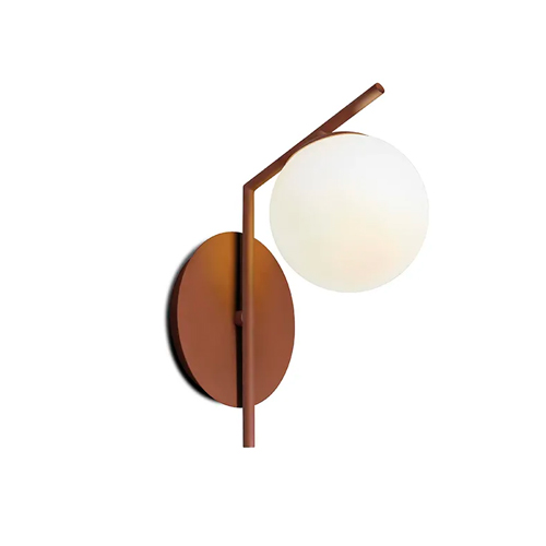 
Esta arandela possui uma base circular metálica em tom cobre fosco fixada à parede. Uma haste fina atravessa a base e se inclina para frente, sustentando um único globo de vidro branco leitoso. O design é assimétrico, moderno e minimalista, lembrando uma forma