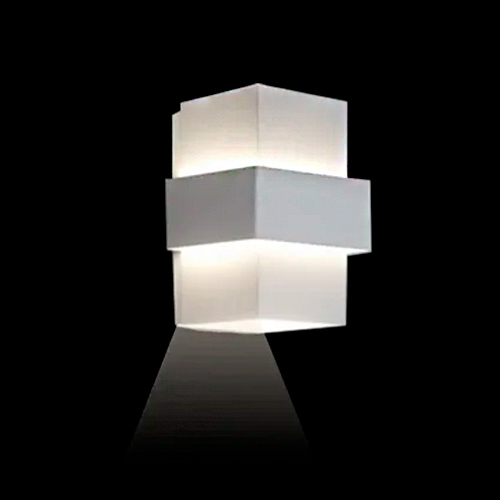 Esta arandela branca (modelo Smart) tem um design geométrico em camadas: dois cubos sobrepostos com um friso central saltado. Ela projeta um facho de luz nítido para baixo, criando um efeito decorativo moderno e minimalista na parede