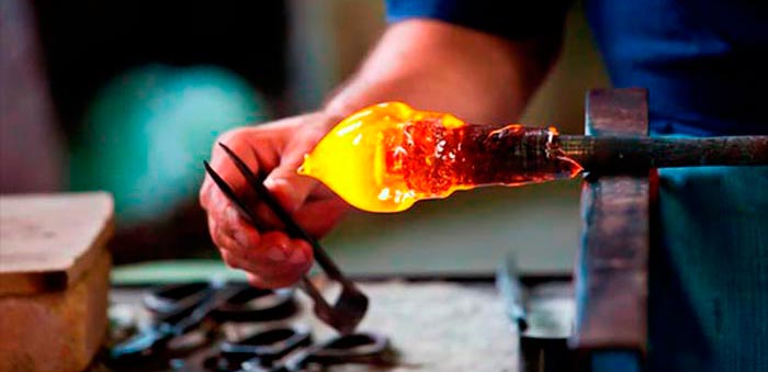 ma mesa do vidreiro com uma bola de vidro incandescente com a ferramenta de forma do vidreiro 