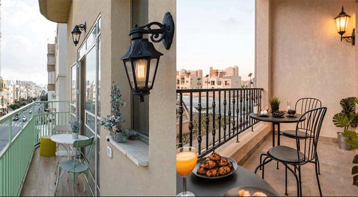 A imagem mostra duas varandas laterais com lanternas de parede clássicas. Esquerda: Varanda estreita, verde-menta, com uma mesinha pequena e vista para uma rua movimentada. Uma lanterna preta maior está em destaque na parede bege. Direita: Varanda maior, com piso de cerâmica e grade preta. Há uma mesa com lanches, suco e duas cadeiras de ferro. Uma lanterna similar ilumina a cena.