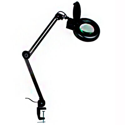 Equipamento com braço articulado de metal, preso a uma superfície (provavelmente uma mesa) por um grampo (tipo sargento). Na ponta do braço, há uma lente de aumento circular com uma luz integrada ao redor, coberta por uma pequena tampa. É ideal para trabalhos, como eletrônica ou artesanato.