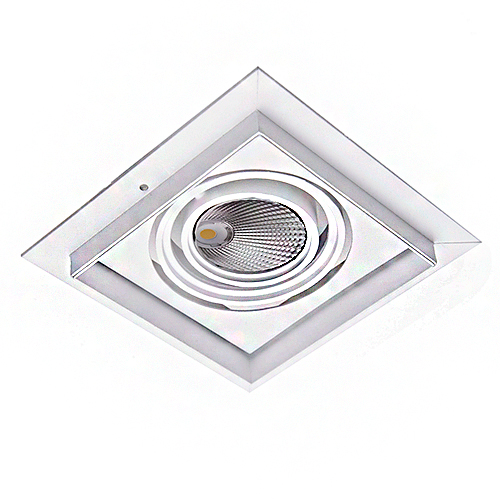 A imagem mostra uma luminária de teto LED semi-embutida. É um spot quadrado, branco, com o centro vazado onde fica uma lâmpada LED redonda, brilhante e inclinável (tipo downlight). Seu design moderno tem recortes em camadas que dão um efeito tridimensional, parecendo um difusor de ar quadrado embutido, mas é um ponto de luz