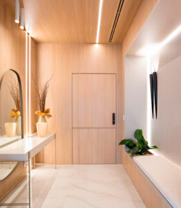 hall de entrada com espelho em um lado e no outro um banco, perfim no teto e no espelho