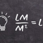 A imagem, que se assemelha a um quadro-negro, mostra uma lâmpada desenhada à esquerda e uma fórmula matemática à direita. A fórmula é M 2 LM ​ =LX. Explicação concisa para um cego (máximo 300 caracteres): É um desenho de lousa preta. Há uma lâmpada acesa desenhada à esquerda. À direita, a fórmula do cálculo de iluminância (lux): lúmens (LM) dividido por metros quadrados (M 2 ) é igual a lux (LX). Isso representa como se calcula a quantidade de luz numa área.