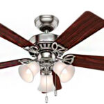 É um ventilador de teto clássico. Possui um corpo central de metal prateado (aço escovado ou cromo). Quatro pás largas de madeira escura (tom mogno ou cerejeira) estão fixadas ao corpo. Na parte inferior, há um kit de luz com três luminárias em forma de sino, com difusores de vidro fosco branco-leitoso. Duas correntes pendentes controlam a luz e a velocidade do ventilador.